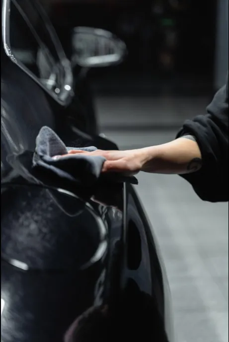 A person is cleaning a black car with a cloth